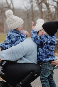 a woman hugging her two sons in a park