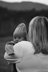 black and white photo of a woman holding a baby in a field