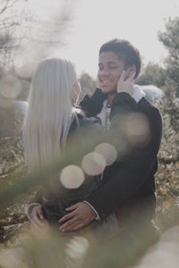 a man and woman hugging in front of a tree