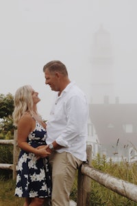 a couple in front of a lighthouse on a foggy day