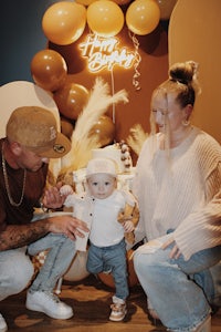 a man and woman with a baby in front of balloons