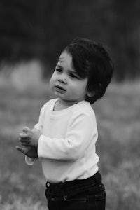 a black and white photo of a baby standing in a field