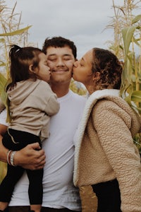 a family kissing in a corn field