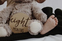 a baby is sitting on a bed with a teddy bear