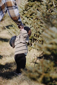 a man holding a baby in a christmas tree field