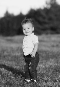 a black and white photo of a baby standing in a field