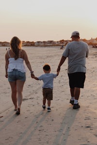 a family holding hands on the beach at sunset