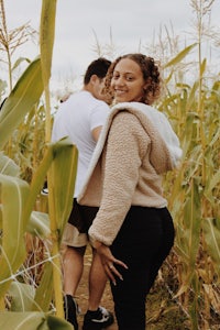 a man and woman standing in a corn field