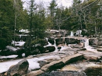 a waterfall in a wooded area covered in snow