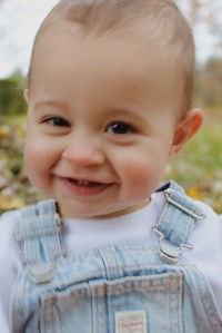 a baby wearing overalls and a white shirt