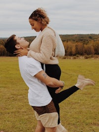 a man is carrying a woman in a field