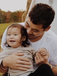 a man is holding a little girl in front of a hay bale