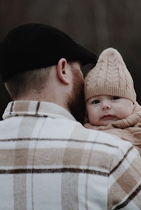 a man holding a baby in a plaid hat