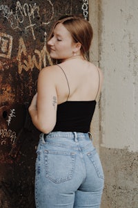 a woman in jeans leaning against a wall