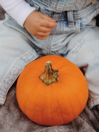 a baby is sitting on a blanket next to a pumpkin